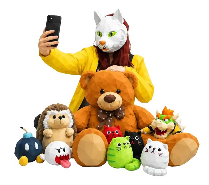 Eine Person mit Katzenmaske macht ein Selfie mit einem Teddybären und bunten Plüschfiguren | © madmoses.